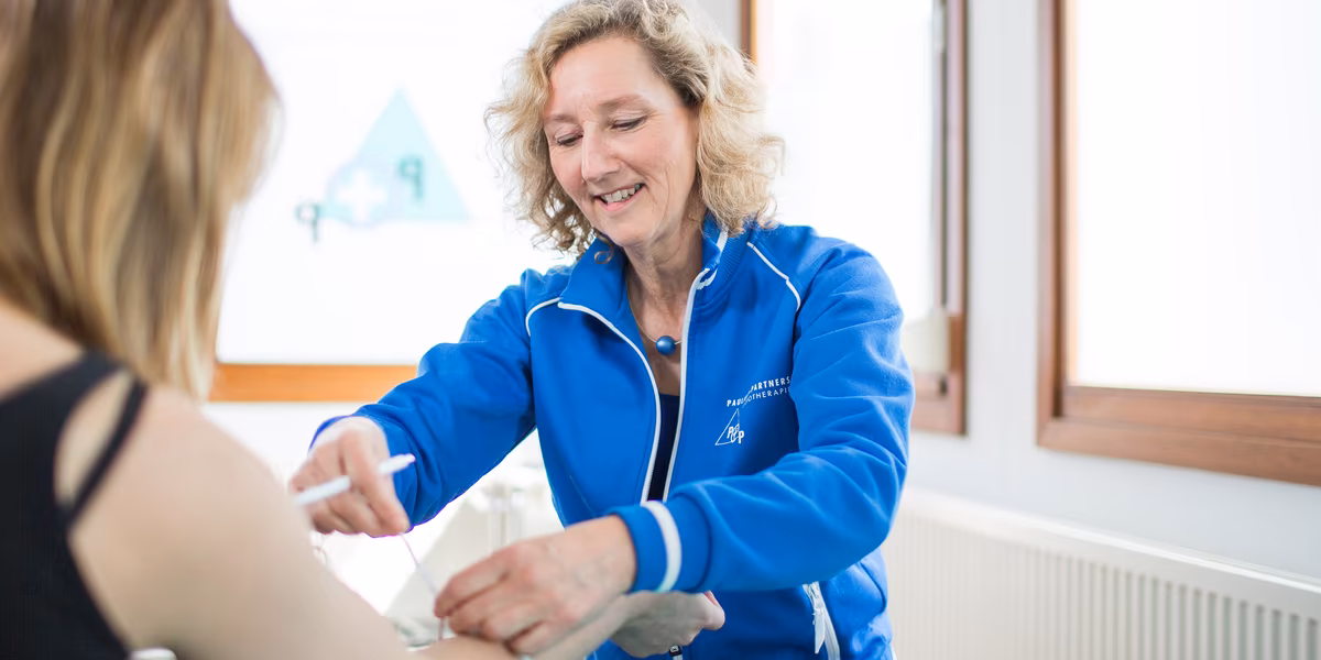 Fysiotherapie behandeling van armklachten Fysiotherapeut onderzoekt arm van patiënt tijdens behandeling