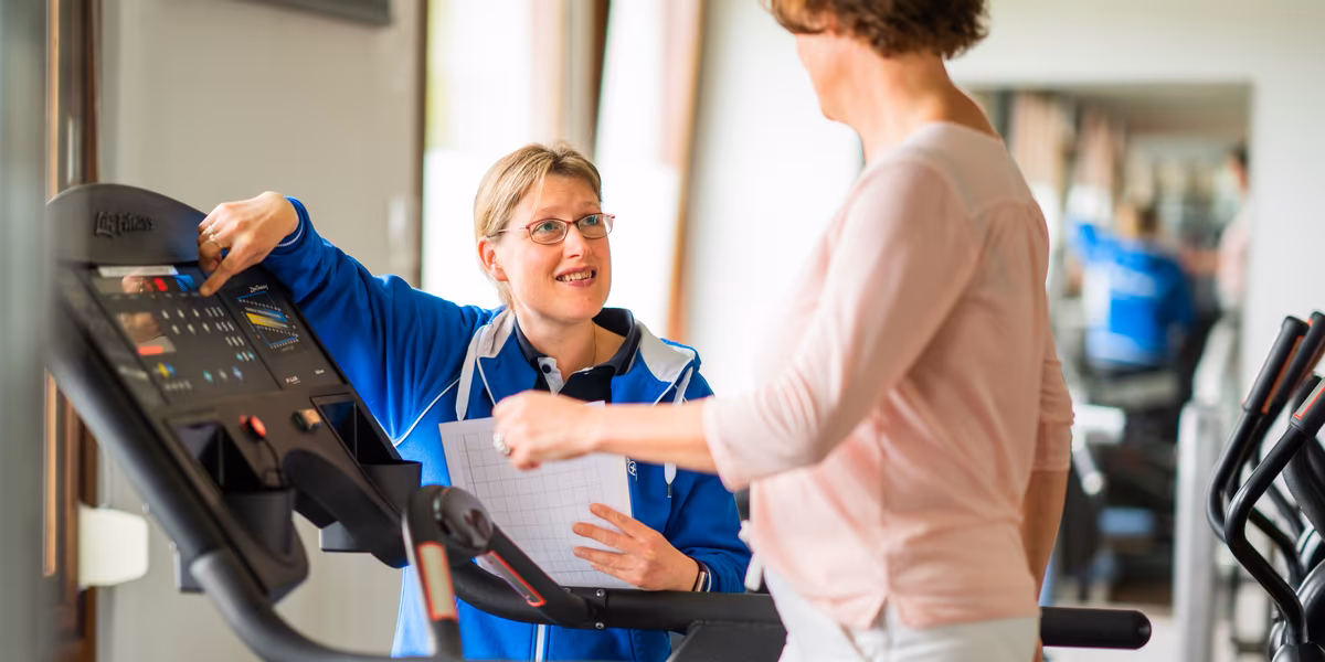Training en revalidatie onder begeleiding van fysiotherapeut Fysiotherapeut begeleidt patiënt tijdens training op loopband in oefenzaal